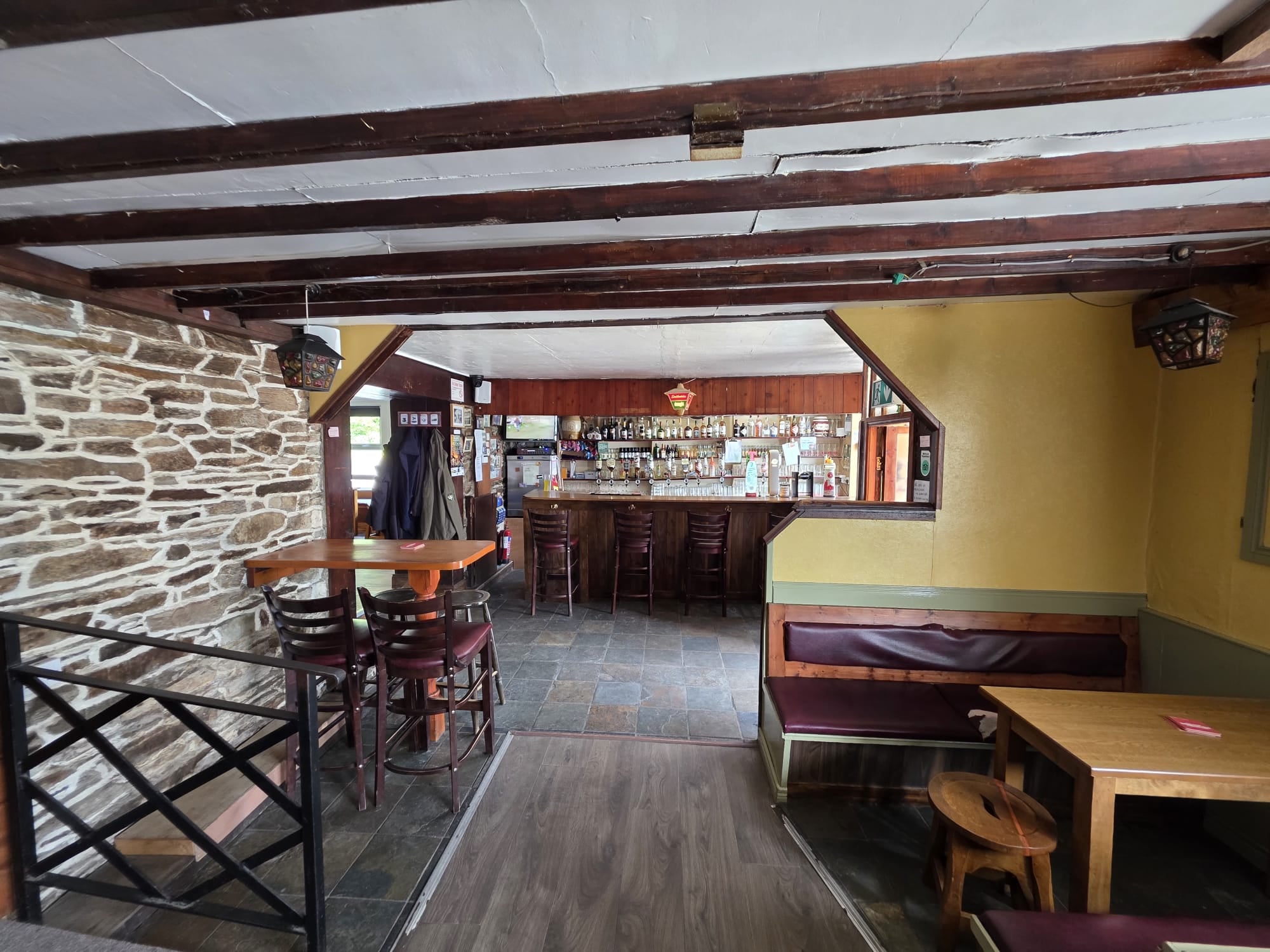 Tables, stools and booth seating by the exposed stone wall at McGowan's